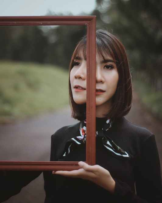 photo of woman holding mirror
